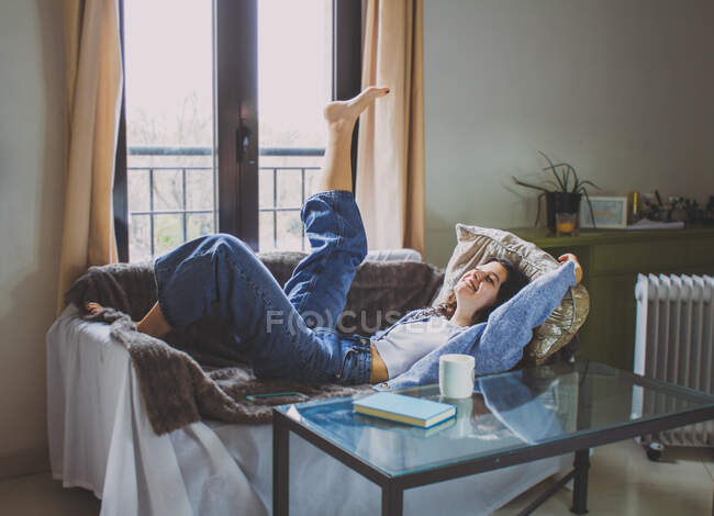 Щаслива молода жінка лежить на дивані, святкуючи перемогу — стокове фото