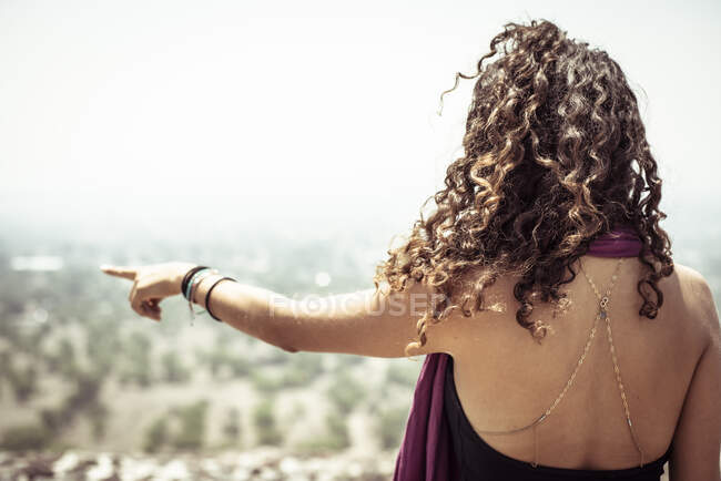 Jovem de cabelos encaracolados mulher mexicana apontando para seco horizonte nebuloso — Fotografia de Stock
