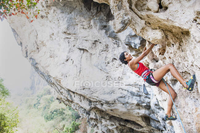 Женщина карабкается на крутую известняковую скалу в Лаосе — стоковое фото