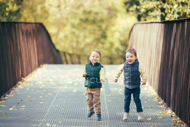 Adorable happy twin boys having fun and jumping in autumn nature — Stock Photo