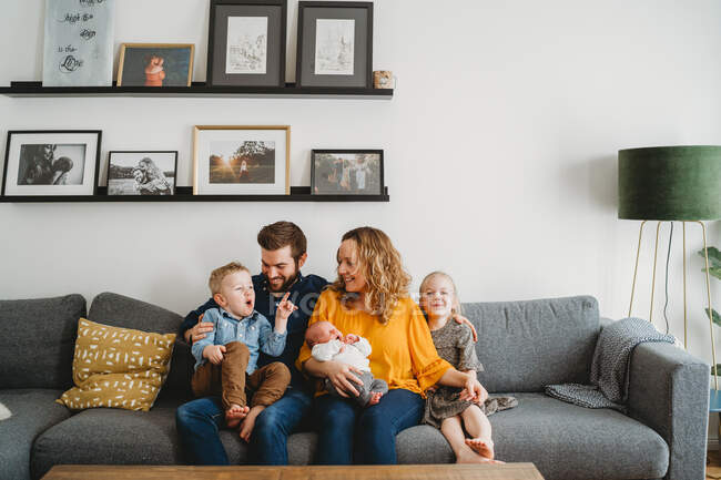 Feliz familia blanca en el sofá en su sala de estar en casa - foto de stock