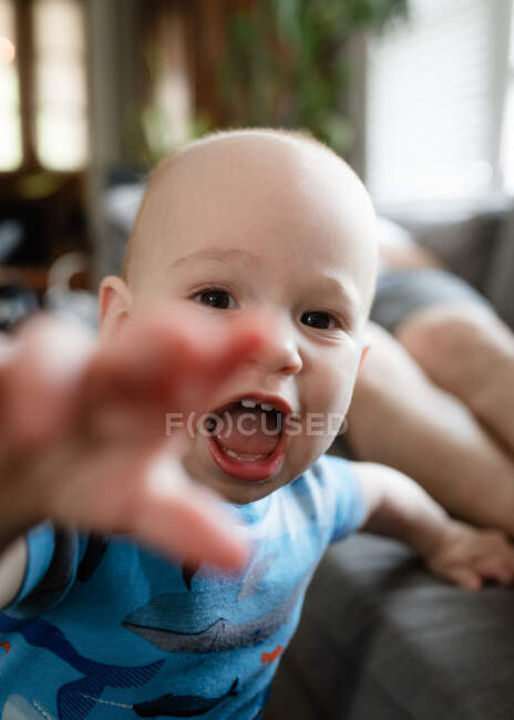 Criança ativa atingindo o telefone da câmera na sala de estar — Fotografia de Stock