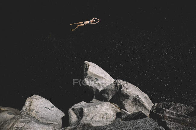 Frau schwimmt in einem dunklen Wasserbecken, das aussieht wie der Weltraum — Stockfoto