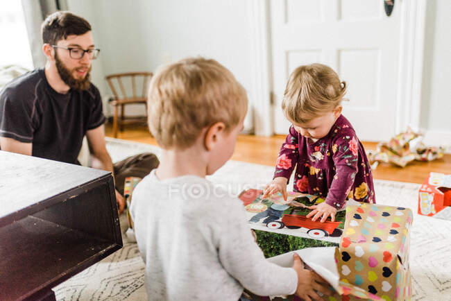 Kinder packen Geburtstagsgeschenke im Wohnzimmer aus und freuen sich — Stockfoto