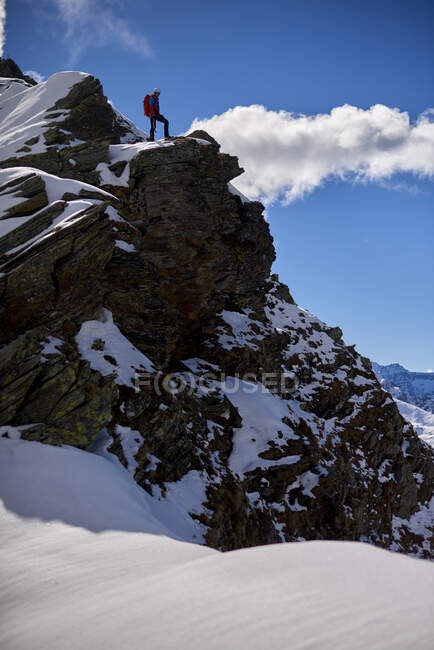 L'uomo si arrampica su una montagna innevata in una giornata di sole a Devero. — Foto stock
