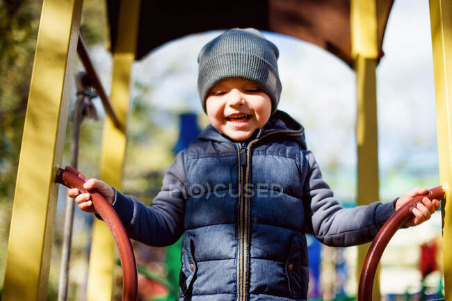 Смеющийся счастливый ребенок на детской площадке, осень на свежем воздухе — стоковое фото