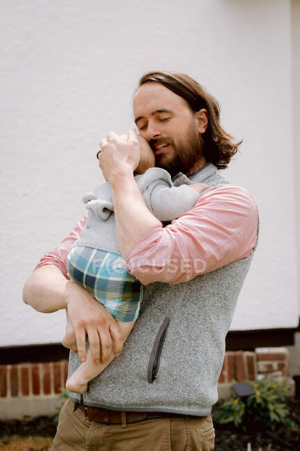 Солодкий батько обіймає немовляти сина в пастельних кольорах надворі навесні — стокове фото