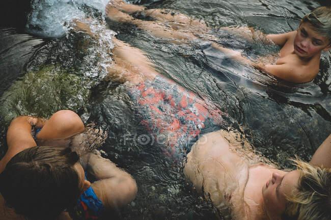 Три мальчика отдыхают в бассейне с текущей водой в сумерках — стоковое фото