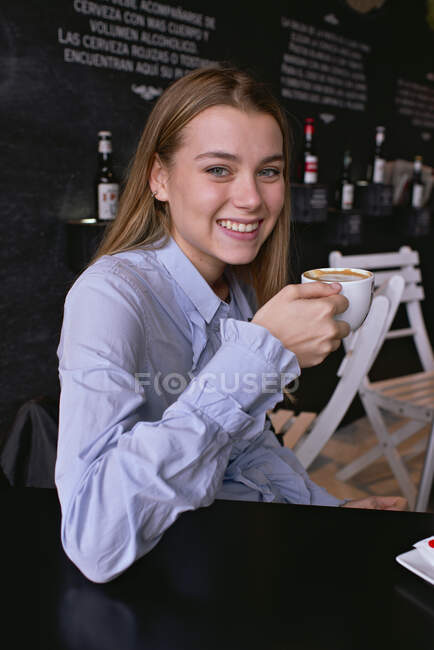 Sorridente splendida ragazza che ha una tazza di caffè in un caffè — Foto stock