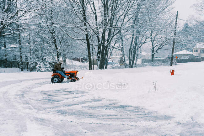 Homem em um trator arar neve em uma calçada durante uma tempestade nor 'easter — Fotografia de Stock