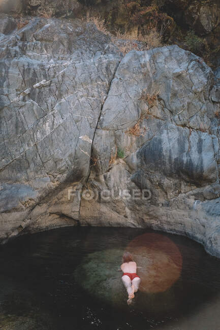 Frau im roten Anzug liegt in einem flachen Pool. — Stockfoto