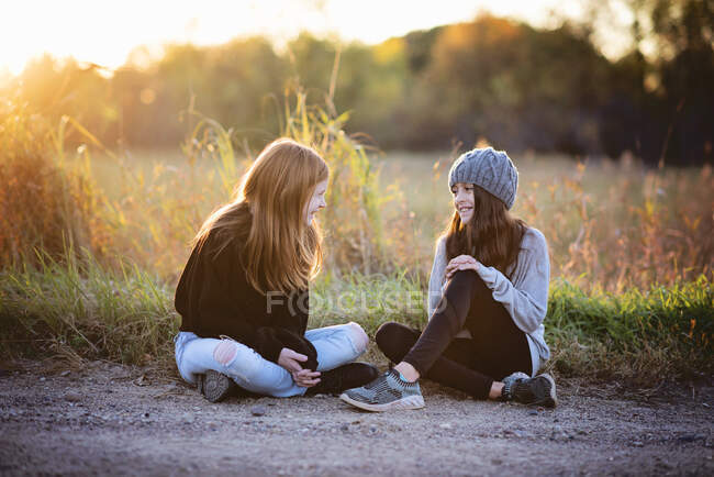 Two beautiful young tween girls in sweaters sitting outside in Fall. — Stock Photo