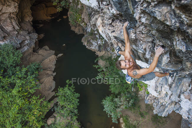 Людина, яка піднімається на навислу вапнякову скелю в Лаосі. — стокове фото