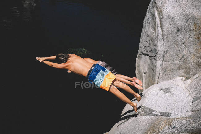 Dos chicos bucean juntos desde un borde del acantilado - foto de stock