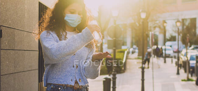 Jovem aplicando gel desinfetante em suas mãos na rua — Fotografia de Stock
