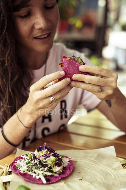 Atractiva alternativa femenina comiendo comida mexicana sana y colorida - foto de stock