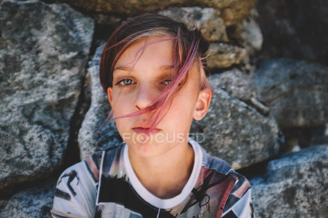 Мальчик с розовыми волосами и графической рубашкой смотрит в камеру — стоковое фото