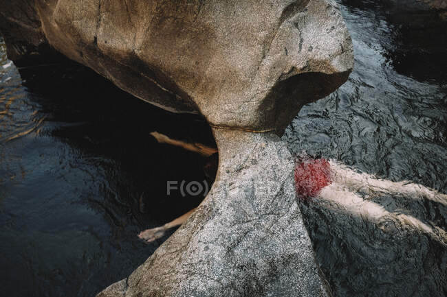 Mulher em um terno de banho vermelho nada debaixo do arco de pedra — Fotografia de Stock
