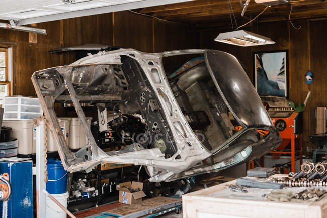 Squelette dépouillé de vieille voiture classique sur un stand de rôtisserie dans le garage — Photo de stock