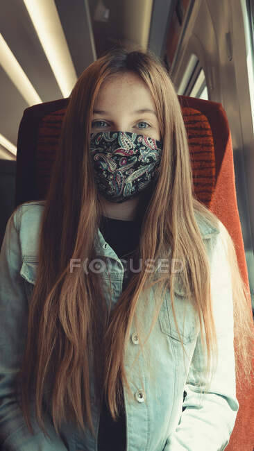 Happy girl on transport wearing a mask looking into camera — Stock Photo