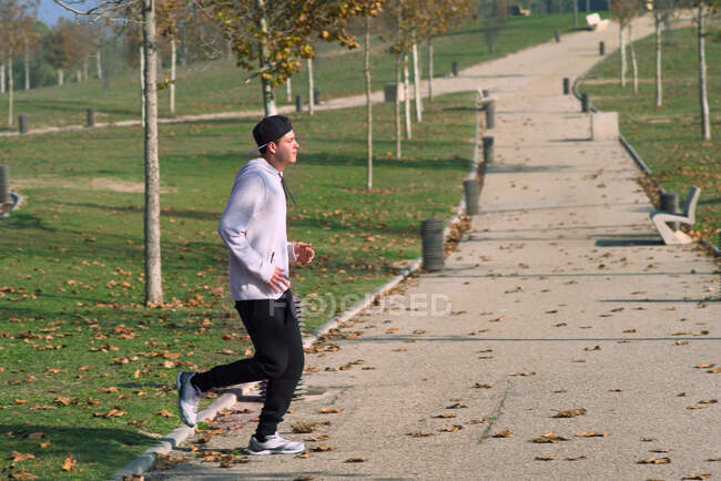 Young sportsman runs through a city park — Stock Photo
