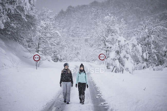 Женщин, идущих по дороге во время снежной бури — стоковое фото