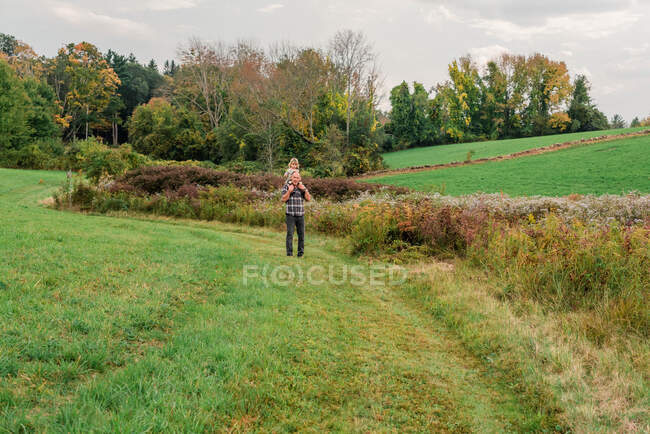 Grandfather and his granddaughter walking in a flowery meadow in MA — Stock Photo