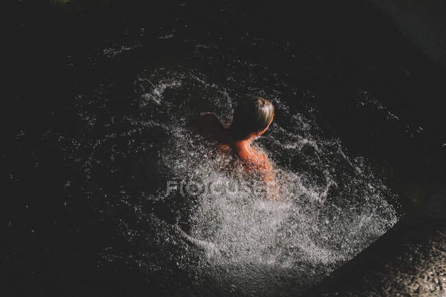 Блондинка виривається з темної води в оточенні бульбашок — стокове фото
