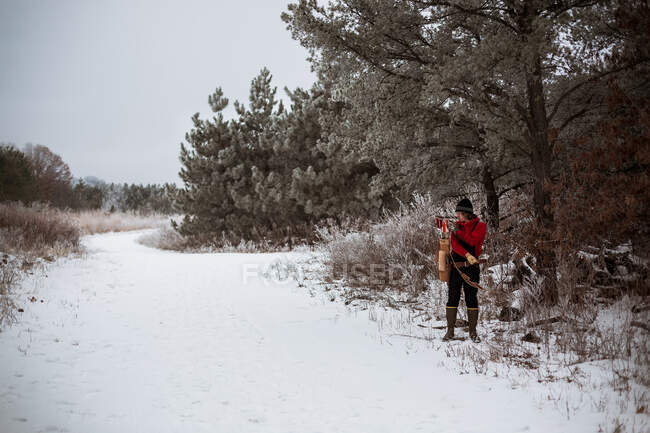 Giovane uomo tirando freccia fuori da faretra vintage nei boschi invernali — Foto stock