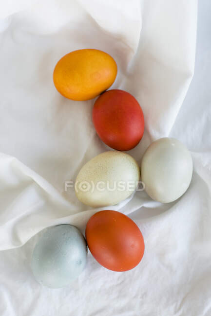 Huevos de Pascua teñidos naturalmente de naranja, amarillo y azul - foto de stock
