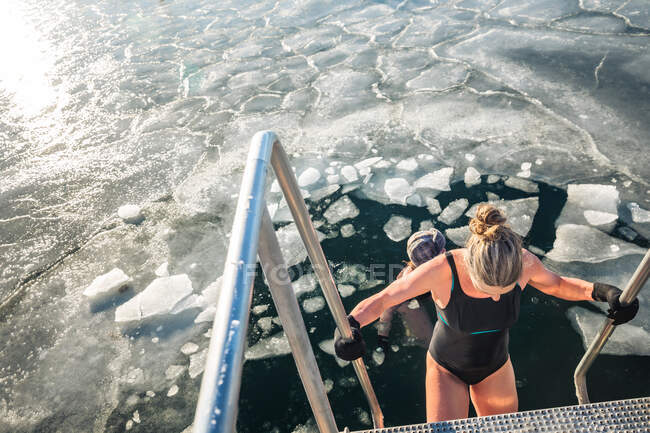Deux baigneurs d'hiver nagent avec des morceaux de glace le jour ensoleillé au Danemark — Photo de stock