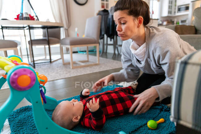 Mother playing with baby boy on the floor. — Stock Photo