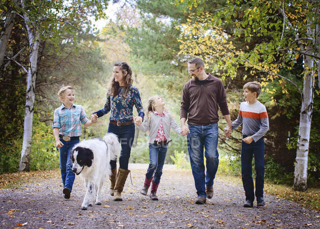 Happy family of five walking down country road with big dog. — Stock Photo
