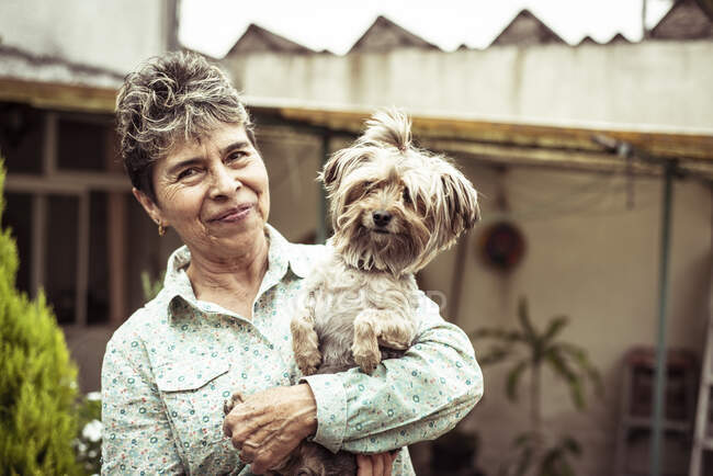 Smiling dog with Mexican woman owner in summer backyard — Stock Photo