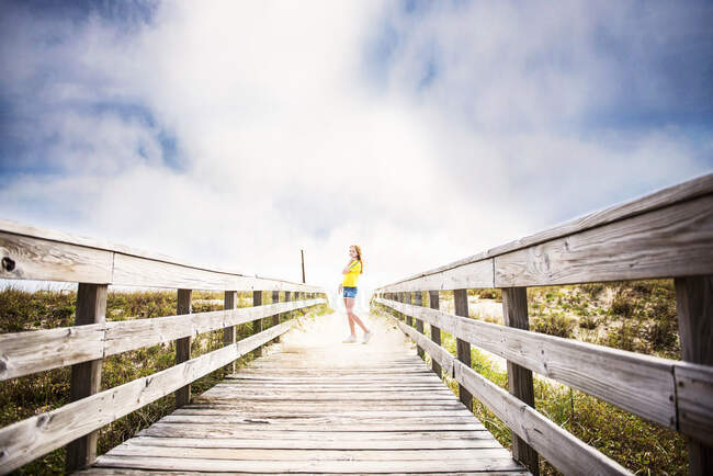 Ruiva Menina no calçadão para o oceano com céu azul e nuvens. — Fotografia de Stock