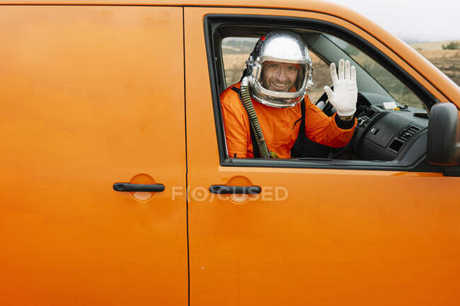 Man dressed as an astronaut waving to camera from the window of the van — Stock Photo