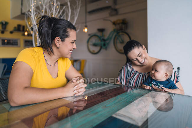 Duas mulheres e um bebê no café conversando e rindo — Fotografia de Stock