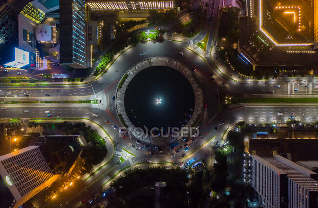 Top down overhead aerial view of moving car traffic at roundabout Vehicle road traffic around Selamat Datang monument in Jakarta, Indonesia at night — Stock Photo