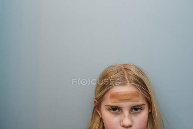 Young girl with bandaid on forehead cropped face with eyes and nose — Stock Photo