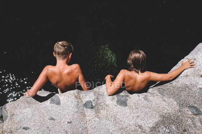 Due ragazzi abbronzati guardano giù da una scogliera nel fiume mezza estate — Foto stock