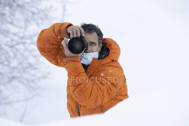 Fotógrafo com uma máscara no meio de uma queda de neve — Fotografia de Stock