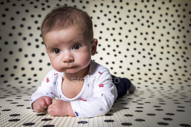 Adorable little baby making funny face while practicing laying on tummy — Stock Photo