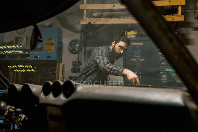 Millennial man in garage fixing timing order in engine of old car — Stock Photo