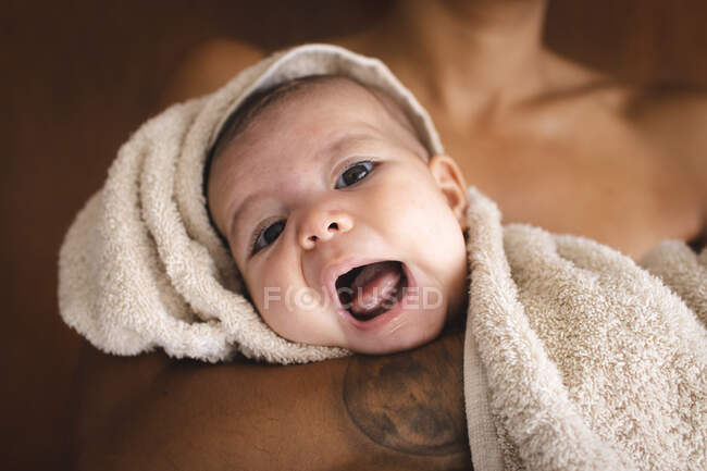Un bel bambino rotolato in un asciugamano aprendo la bocca con sua madre — Foto stock