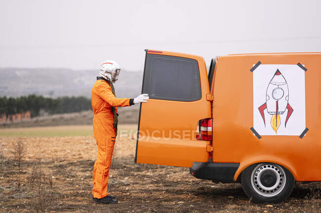 Man dressed as an astronaut opening the door of the van — Stock Photo