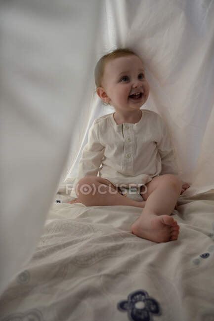 Bambina nascosta sotto il lenzuolo bianco — Foto stock