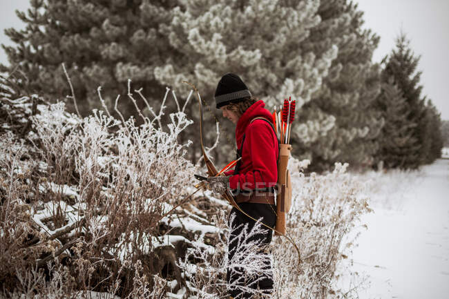 Teenie-Junge betrachtet Tierfalle im Winter Wisconsin mit Pfeil und Bogen — Stockfoto