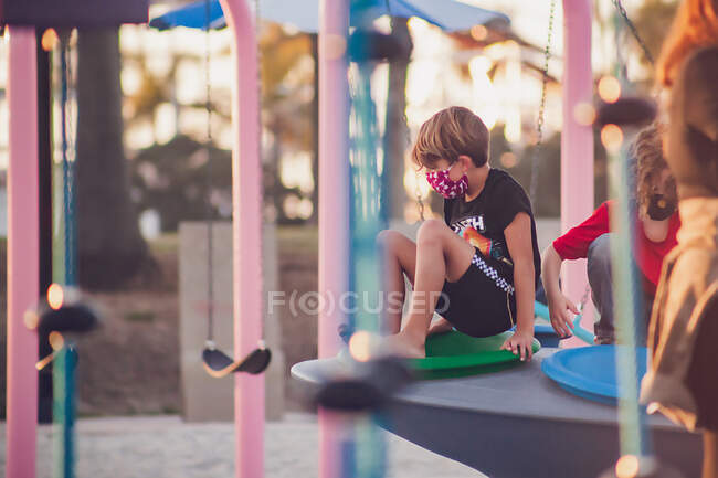 Menino usando uma máscara jogando sozinho em um playground — Fotografia de Stock