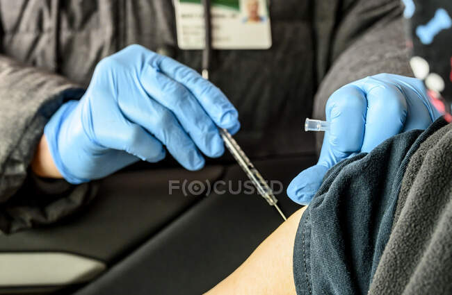 Медсестра, вводящая вакцину против ковида-19 женщине в руку в распределительном пункте. — стоковое фото