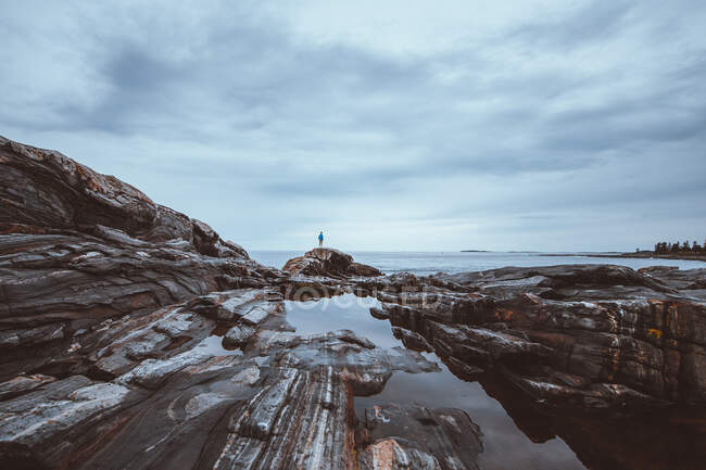 Um adolescente tem vista para o oceano enquanto está em pé na costa do Maine. — Fotografia de Stock